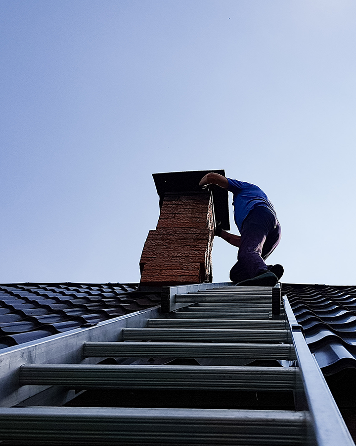 Certified chimney professional on roof with ladder