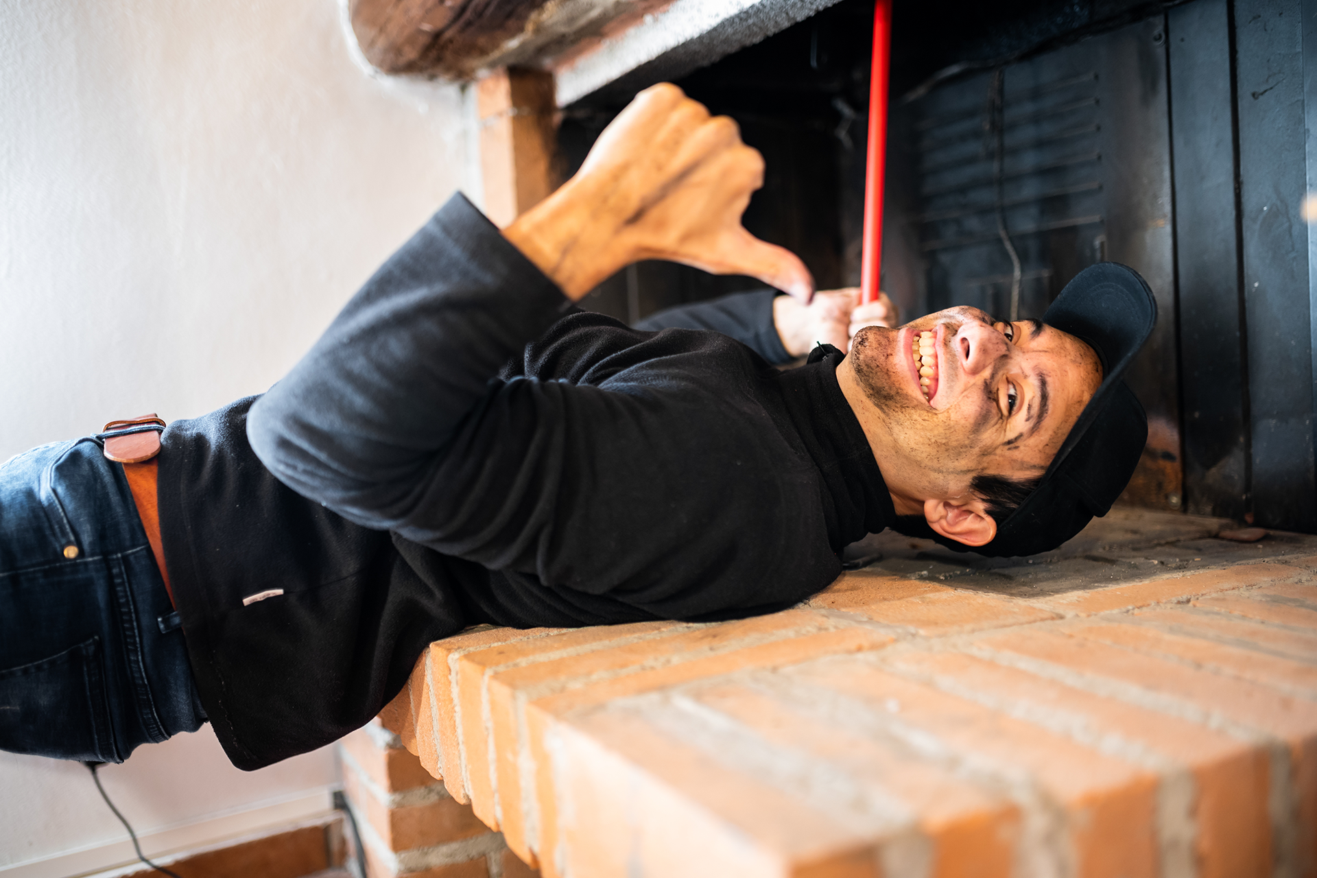 Chimney expert sweeping fireplace with specialized tools